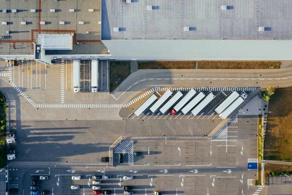 Aerial view of trucks lined up at distribution-center loading docks at dusk.